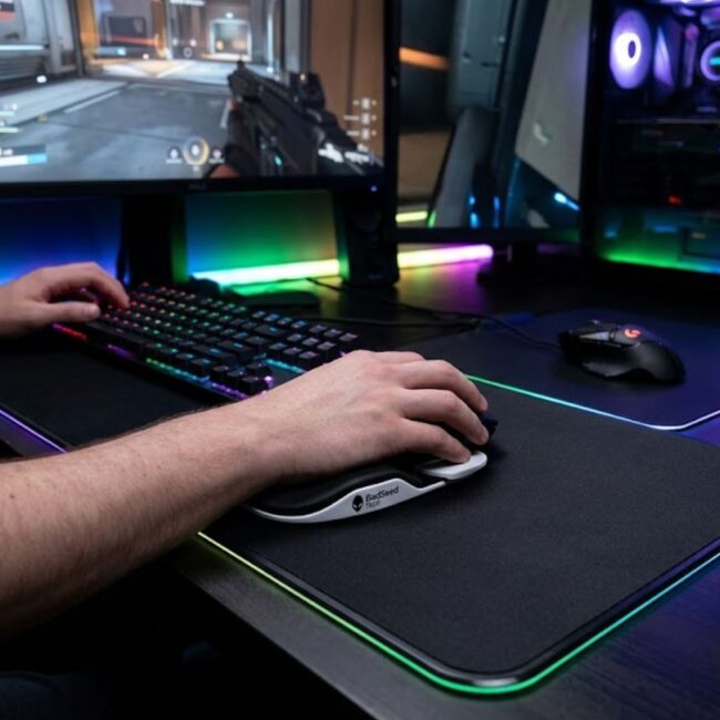 BadSeed Tech Carpio 2.0 gliding wrist rest on dark gaming desk with RGB setup